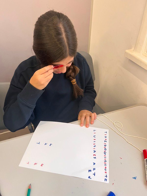 Aluna observando detalhes com lupa em atividade da oficina de férias